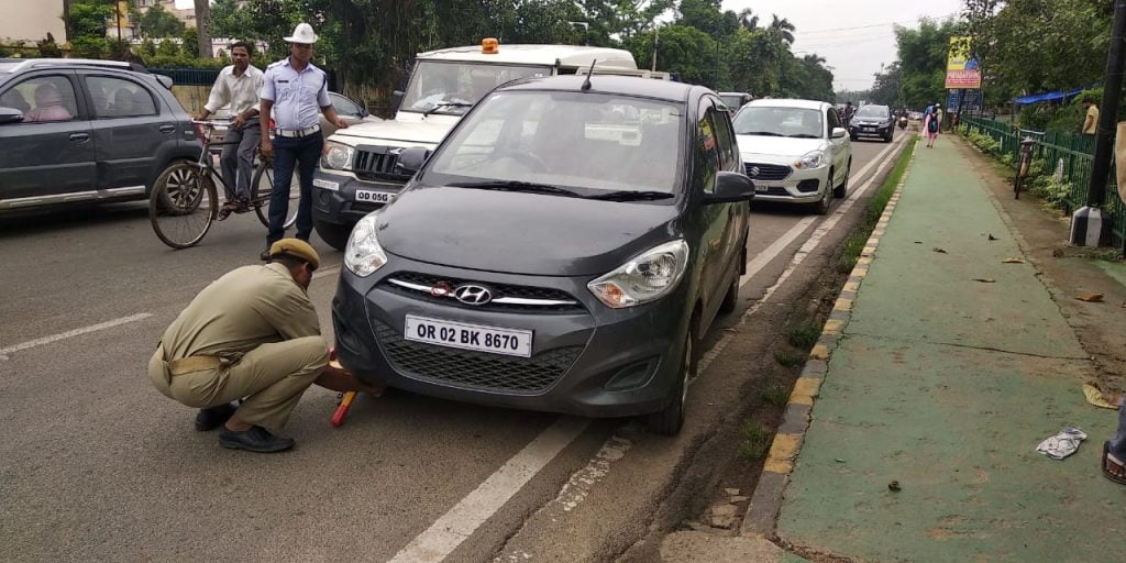 STRIENGENT MEASURES: A cop fixes a jammer on a illegally parked vehicle in Bhubaneswar on Wednesday. OB Photograph